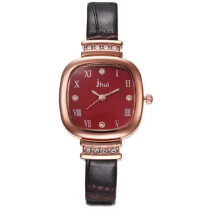 Close-up of square red watch face with rose gold Roman numerals and leather strap