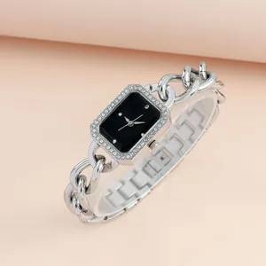 Detail view of square silver watch with rhinestone bezel and black dial on pink background