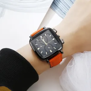 Detail of square black quartz watch with orange leather strap worn on wrist