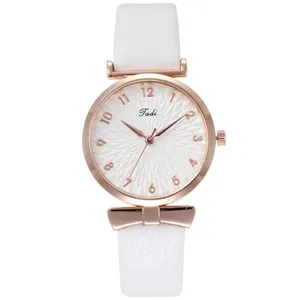 Detail of rose gold watch case with white faux leather strap and bow decoration