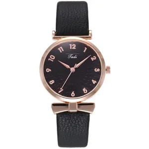 Detail of rose gold watch with black leather strap and unique bow-shaped metal lugs
