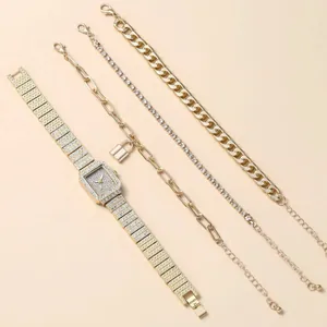 Détail d'un coffret montre dorée et trois bracelets assortis sur un tissu beige doux