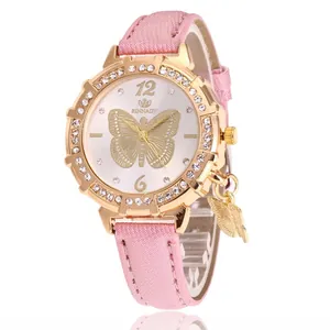 Gros plan montre RINNADY avec bracelet rose, lunette en cristal et breloque papillon