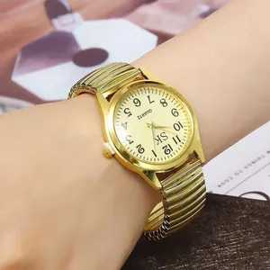 Detail of gold quartz watch with elastic metal strap and numeric dial shown on wrist