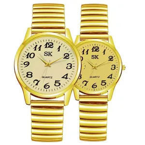 Detail of gold quartz couple watches with numeric dials and stretch metal bands