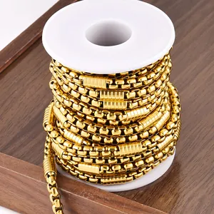 Detailed close-up of golden stainless steel box chain with textured cylinder accents on a spool