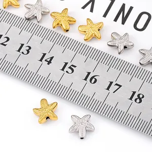 Gold and silver starfish spacer beads with textured finish shown on measuring scale