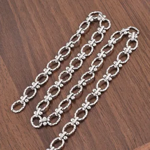 Detail of silver stainless steel chain with sparkling diamond-cut texture on wood background