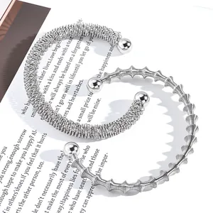 Böhmische verstellbare Manschettenarmbänder aus Edelstahl in Silber auf einem Buch