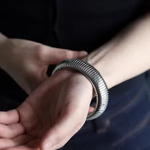 Macro detail of silver stainless steel wide elastic snake chain bracelet on wrist