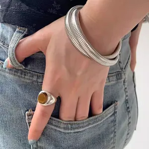 Detail of silver Tubogas snake bracelet and tiger eye stone ring on denim pocket