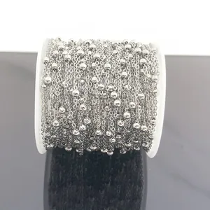 Detailed macro view of silver stainless steel satellite beaded chain on a white plastic spool