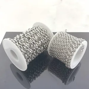 Macro view of two types of polished stainless steel oval chains on white plastic spools