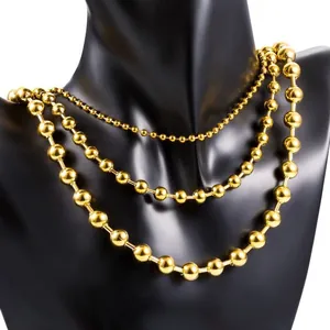 Detailed view of three polished gold ball chain necklaces on a black neck mannequin