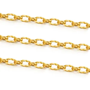 Detail einer gedrehten ovalen Gliederkette aus goldenem Edelstahl mit Struktur