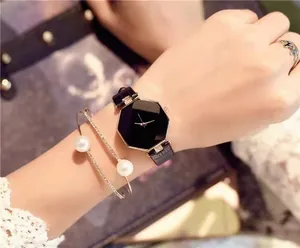Close-up of octagonal black face watch paired with a pearl and diamond gold bangle