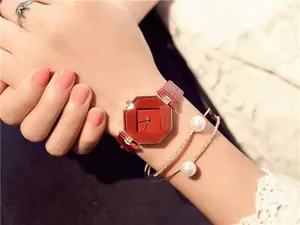 Detail of red octagonal quartz watch paired with pearl bracelet and crown ring set