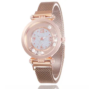 Detail of rose gold mesh watch band and round dial with sparkling floating crystals