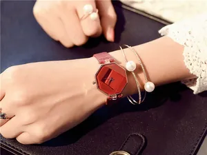 Close-up of women's red octagonal quartz watch paired with elegant pearl bracelets