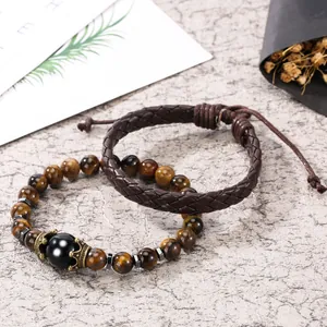 Detail of tiger eye bead bracelet with crown charm and brown woven leather wristband