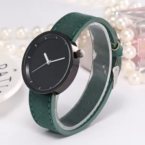 Minimalist watch featuring a black dial and dark green suede strap with fine stitching