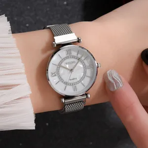 Detail of a silver mesh strap watch with a rhinestone dial and Roman numerals on a wrist