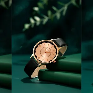 Montre quartz pour femme élégante avec boîtier or rose et bracelet en cuir noir sur fond vert