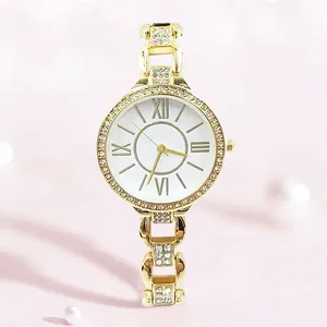 Elegante goldene Quarzuhr mit Strass und römischen Ziffern auf sanftem rosa Hintergrund