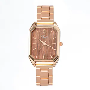 Détail de la montre octogonale en or rose avec un cadran texturé en bois marron chic
