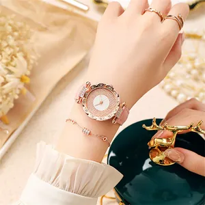 Nahaufnahme einer roségoldenen Strassuhr mit rosa Lederarmband und Schmuck am Handgelenk