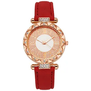 Nahaufnahme der roségoldenen Uhr mit Strasssteinen, römischen Ziffern und rotem Wildleder