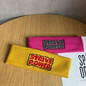 Détail des bandeaux en tricot rose et jaune avec l'inscription Strive Power brodée