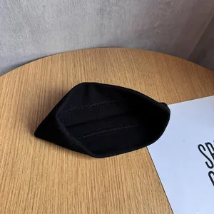 Gros plan sur la texture du bonnet en tricot noir posé sur une surface en bois épurée