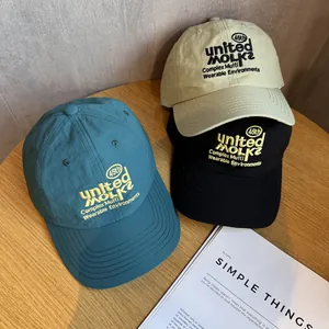 Drei bestickte schnelltrocknende Baseballkappen in Blau, Beige und Schwarz auf Holz