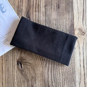 Detailed view of black knitted headband with vertical texture on a wooden surface