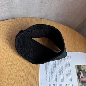 Détail du bandeau tricoté noir avec texture côtelée verticale sur une surface en bois