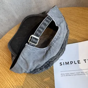Detail view of denim beret with silver adjustable buckle on a wooden table surface