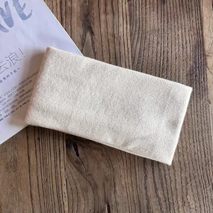Detailed view of cream knitted headband texture on a natural wooden background