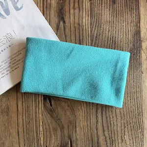Detailed close-up of a turquoise knitted headband on a rustic wooden surface with a magazine