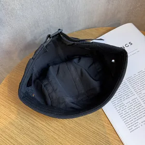 Detail of black quick-dry cap showing 100% polyester label and adjustable buckle strap