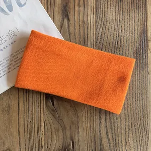 Close-up of bright orange knitted elastic sports headband on a wooden table texture
