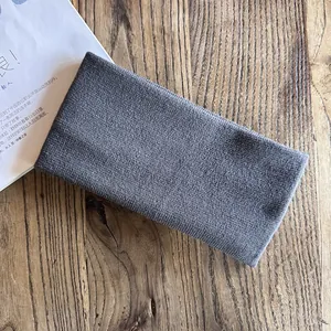 Macro detail of dark grey wide knit headband with soft texture on a wooden surface
