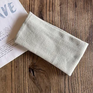 Detail of oat-colored ribbed knit headband folded on a natural wooden background