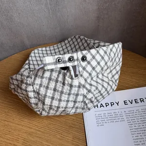Béret japonais à carreaux noirs et blancs avec boutons métalliques sur une table en bois