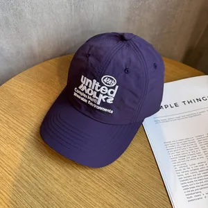 Detail der lila schnelltrocknenden Baseballkappe mit weißer Bestickung auf Holztisch