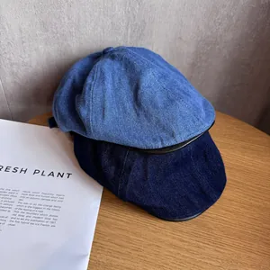 Retro denim newsboy caps in light and dark blue with black leather brim detail on wood
