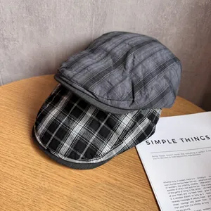 Retro British style checkered flat caps in grey and black white on a wooden desk