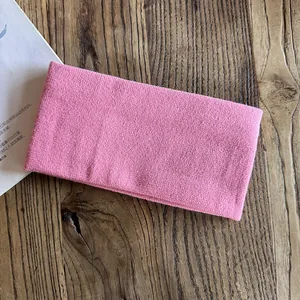 Pink knitted elastic headband for sports and daily wear on a vintage wood background
