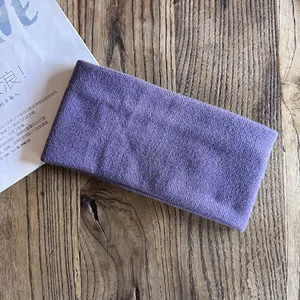 Close-up of purple knitted headband showing soft ribbed texture on a wooden surface