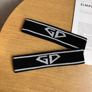 Close-up of two black knitted sports headbands with white letters on a wooden background